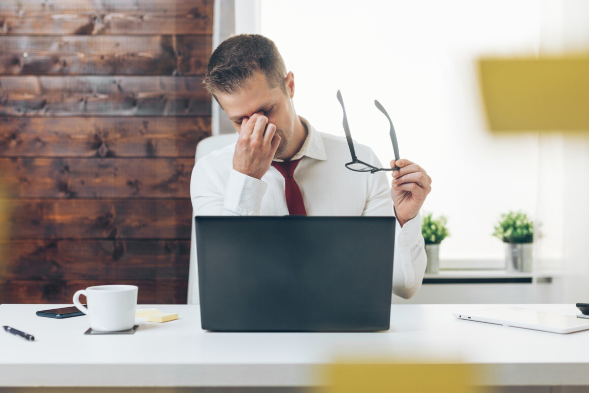 Overworked business executive sitting at a desk with his head in his hand