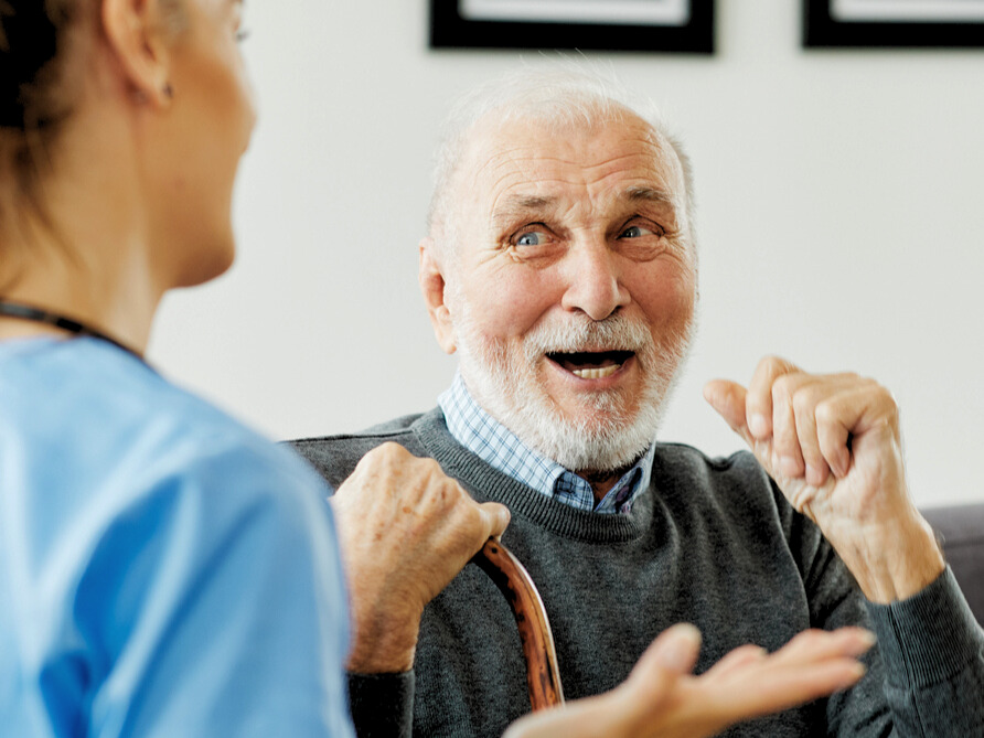 Senior living staff member speaking with a resident in a community setting.